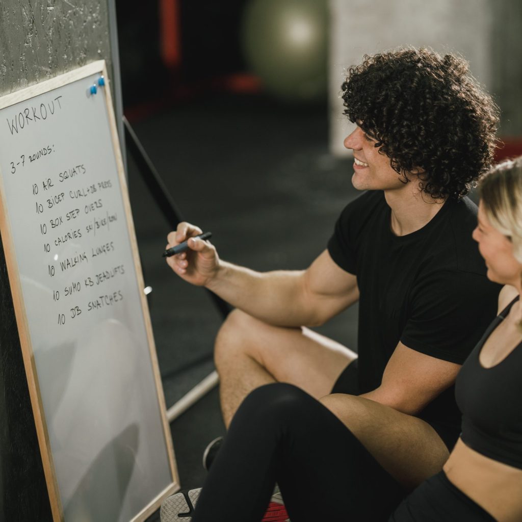An attractive woman talking about exercise plan with her personal trainer at the gym.
